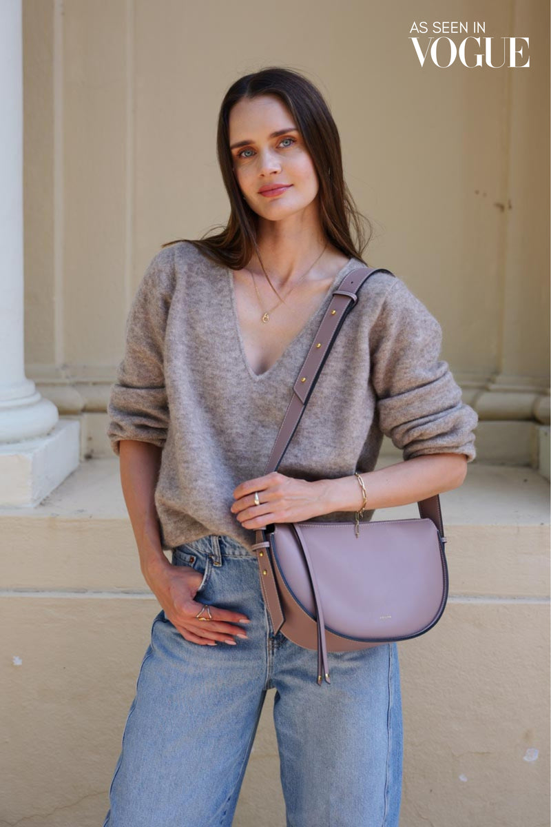 woman standing and modeling a handbag with "as seen in vogue" text